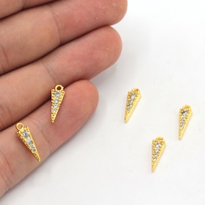 May include: Four gold-tone triangle-shaped charms with clear rhinestone accents. Each charm has a loop at the top for attaching to jewelry.