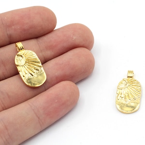 May include: Two gold-toned metal charms in the shape of an oval with a sun design. The charms have a loop at the top for attaching to a necklace or bracelet.