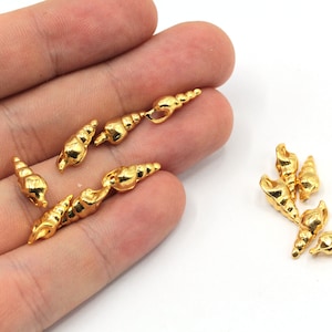 May include: A group of ten gold-colored seashell charms. The charms are small and detailed, with a realistic seashell design. They are perfect for adding a touch of nautical charm to jewelry or crafts.