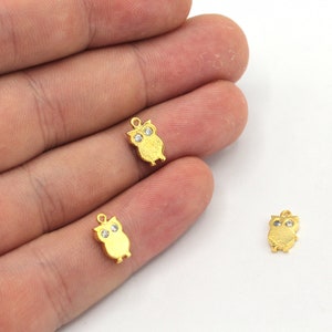 Op de afbeelding: Drie gouden uil bedels met heldere strass steentjes als ogen. De uilen kijken naar voren met hun vleugels uitgespreid.