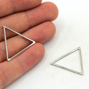May include: Two silver triangle shaped metal charms. The charms are open on one side and have a smooth, shiny finish.