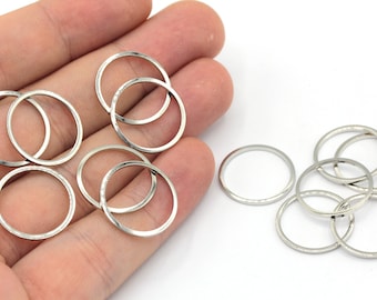 May include: A set of silver jump rings, perfect for jewelry making or crafting projects. The rings are arranged in two groups, with some overlapping.