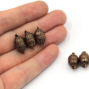 May include: Five antique gold-toned metal oval beads with intricate designs. The beads have a loop on each end for attaching to jewellery or other crafts.
