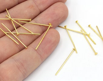 May include: A close-up of a pile of gold-colored head pins. The pins are about 1 inch long and have a flat head.