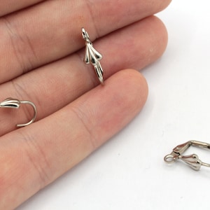 May include: Three silver earring hooks, two are closed and one is open. The hooks are designed with a small, decorative, teardrop-shaped detail at the bottom.
