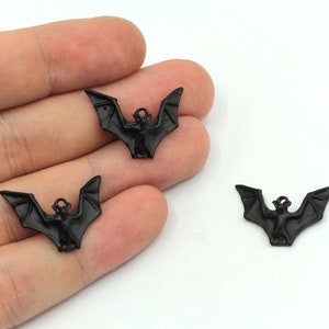 Peut inclure: Trois breloques en m&eacute;tal noir en forme de chauve-souris avec une boucle de suspension. Les chauves-souris sont en position de vol, les ailes d&eacute;ploy&eacute;es.