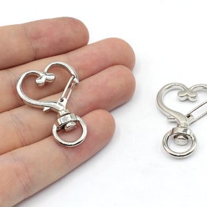 May include: Two silver heart-shaped swivel clasps with a spring-loaded gate. The clasps have a small heart detail on the top.