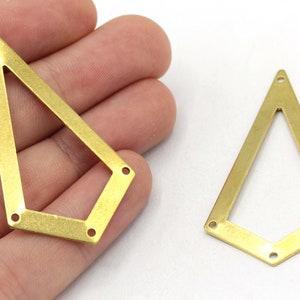 May include: Two gold-toned metal geometric shapes with open centers and holes around the edges. The shapes are similar in size and design, with one being slightly larger than the other.