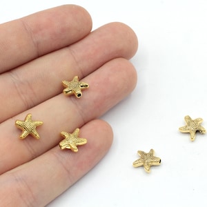 May include: Five gold-colored starfish-shaped beads. The beads have a textured surface and a hole in the center for stringing.
