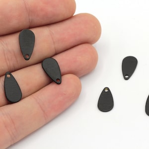 May include: Six black metal teardrop-shaped charms with a small hole at the top.