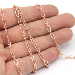 May include: A close-up of a rose gold chain with oval links. The chain is lying on a hand, with the links visible.