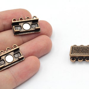 May include: Three antique gold-toned metal clasps for jewelry making. Each clasp has four loops and a decorative design.