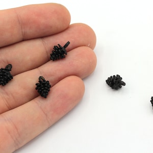 Könnte beinhalten: Fünf schwarze, plastikförmige Tannenzapfen-Anhänger mit einer Schlaufe oben.