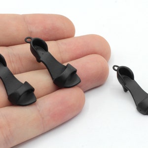 May include: Three black miniature high-heeled sandals with open toes.