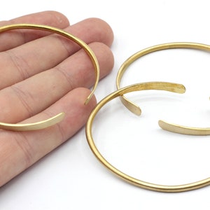 May include: Three gold-toned metal bangles, two of which are stacked on top of each other.