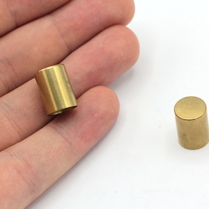 May include: Two gold-colored metal cylindrical caps. The caps are smooth and have a slightly rounded top.