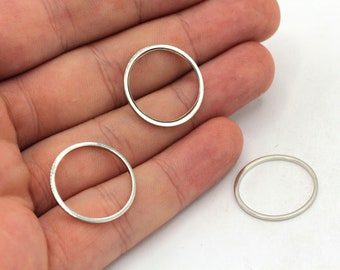 May include: Three silver metal rings of different sizes on a hand.