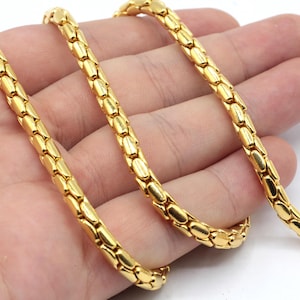 Könnte beinhalten: Eine goldene Kettenkette mit einem Schlangenketten-Design. Die Kette besteht aus kleinen, ovalen Gliedern.