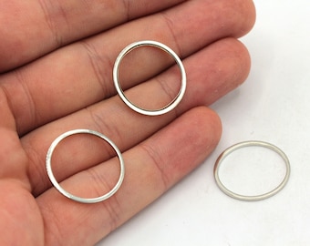 May include: Three silver metal rings of different sizes, lying on a hand.