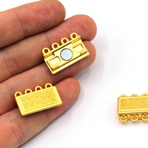 May include: Three gold-tone metal clasps for necklaces or bracelets. Two clasps have a textured design and four loops. One clasp has a magnetic closure and four loops.