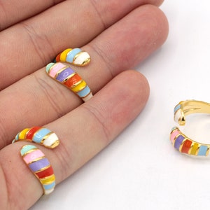 May include: Three gold rings with colorful enamel stripes. The rings are open and can be adjusted to fit different finger sizes.