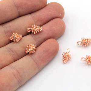 Könnte beinhalten: Sechs roségoldene Metall-Kiefernzapfen-Anhänger mit einer Öse zum Anbringen an Schmuck oder anderen Bastelarbeiten.