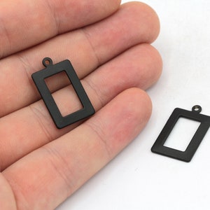 May include: Two black metal rectangular picture frame charms with a loop at the top for hanging.