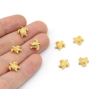 May include: A collection of ten gold-coloured turtle charms. The charms are small and detailed, with a textured surface. They are perfect for adding a touch of whimsy to jewellery or crafts.