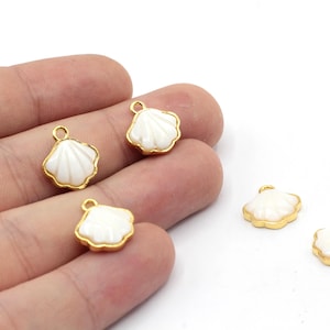 May include: Four gold-toned shell charms with white shell inlays. The charms have a loop at the top for attaching to jewelry.