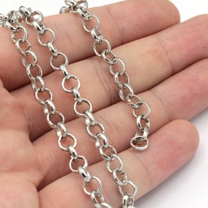 Può includere: Una catena d'argento con maglie rotonde. La catena è appoggiata su una mano.