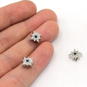 May include: Three silver star-shaped charms with a blue center stone and clear rhinestones around the edge.
