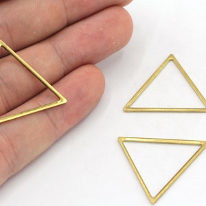 May include: Three gold-toned metal triangle shapes. The triangles are hollow and have a smooth, polished finish.