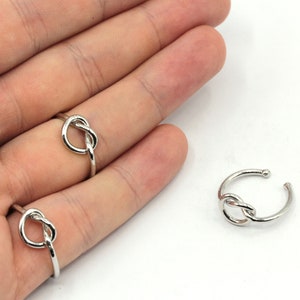 May include: Two silver knot rings. The rings are simple and elegant, with a knot design that is both modern and timeless.