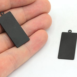 May include: Two black metal rectangular tags with a hole at the top for hanging.