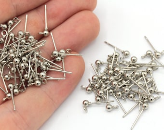 May include: A pile of silver-toned earring posts with small round balls on the ends. The posts are about 1 inch long.