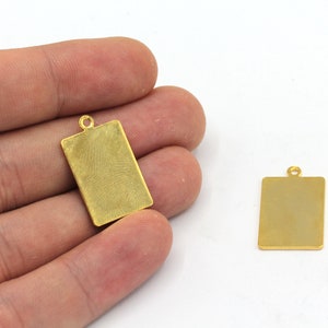 May include: Two gold-colored metal rectangular tags with a loop at the top. The tags are blank and ready for personalization.