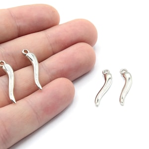 Puede incluir: Cuatro abalorios de chile en forma de chile de color plateado con un bucle para sujetar a joyas u otras manualidades.