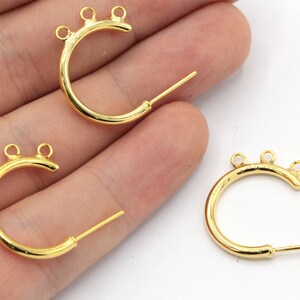 May include: Three gold-colored earring components. Each component has a curved, crescent-like shape with three small loops at the top and a straight post extending from the bottom. The earrings are displayed against a white background.