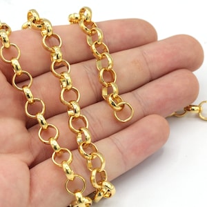 May include: Close-up of a gold-colored chain necklace with a rounded link design. The chain is made of metal and has a bright, shiny finish. The necklace is shown against a white background.