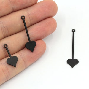 May include: Three black metal heart-shaped charms with a loop at the top and a long, thin stem extending from the bottom of the heart.
