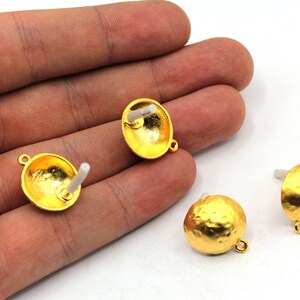 May include: Three gold-toned metal earring findings with a hammered texture. Each finding has a loop on one side and a post on the other side.