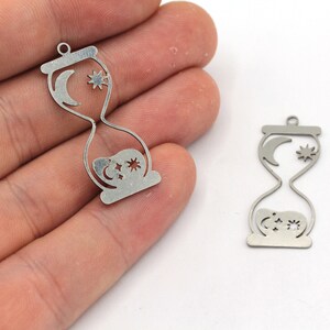 May include: Two silver metal hourglass charms with a crescent moon and stars design.
