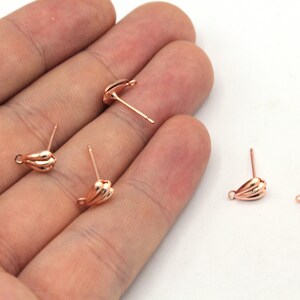 May include: Four rose gold earring findings with a teardrop shape and a loop at the top. The findings are on a white surface.