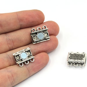 May include: Three silver-toned metal clasps for jewelry making. Two clasps have a round magnetic closure and one has a decorative patterned closure.
