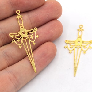 May include: Two gold-coloured metal sword charms with a starburst design and a dangling chain of stars.