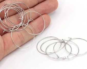 May include: A set of silver hoop earrings. The hoops are made of thin metal and are about 1 inch in diameter.