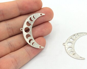 Puede incluir: Dos dijes de metal plateado en forma de media luna con fases de la luna recortadas. Los dijes tienen un acabado cepillado y son perfectos para la elaboración de joyas.