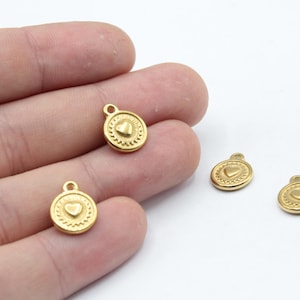 以下が含まれることがあります： ハートのデザインが施された金色の金属製チャームが4つ。各チャームの上部には、ネックレスやブレスレットに取り付けるためのループが付いています。