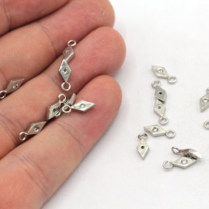 May include: Silver-toned metal diamond-shaped charms with jump rings. The charms have a small hole in the center of each diamond.