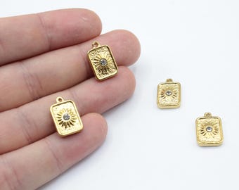 May include: Three gold-toned metal charms with a square shape and a raised design featuring a clear rhinestone in the center.
